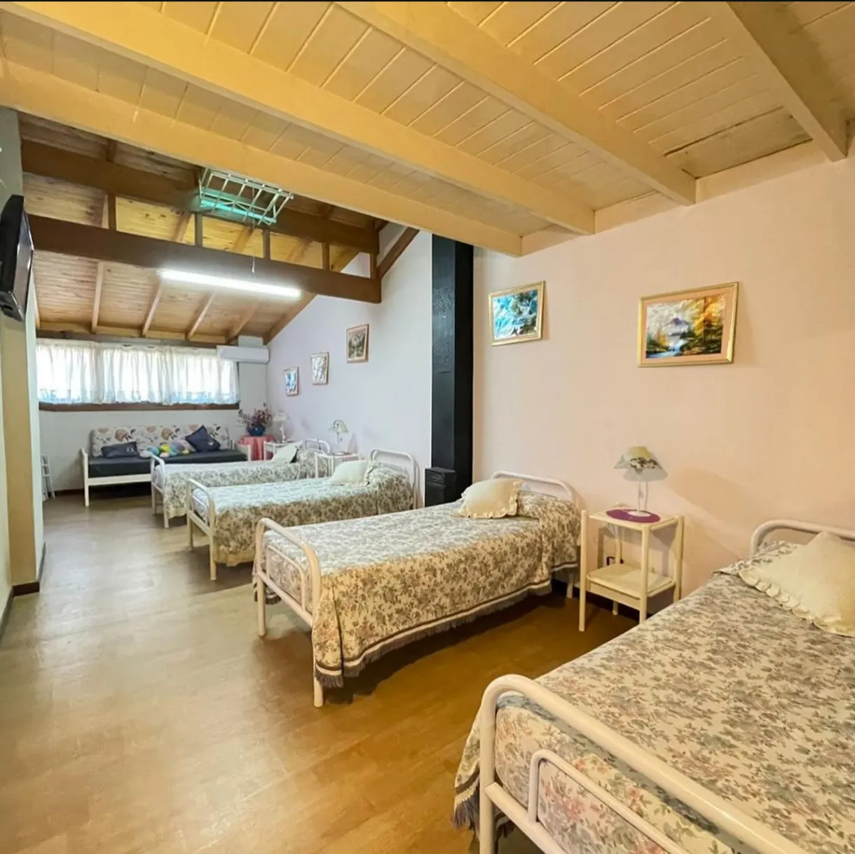 Dormitorio compartido amplio con camas individuales y techo de madera
