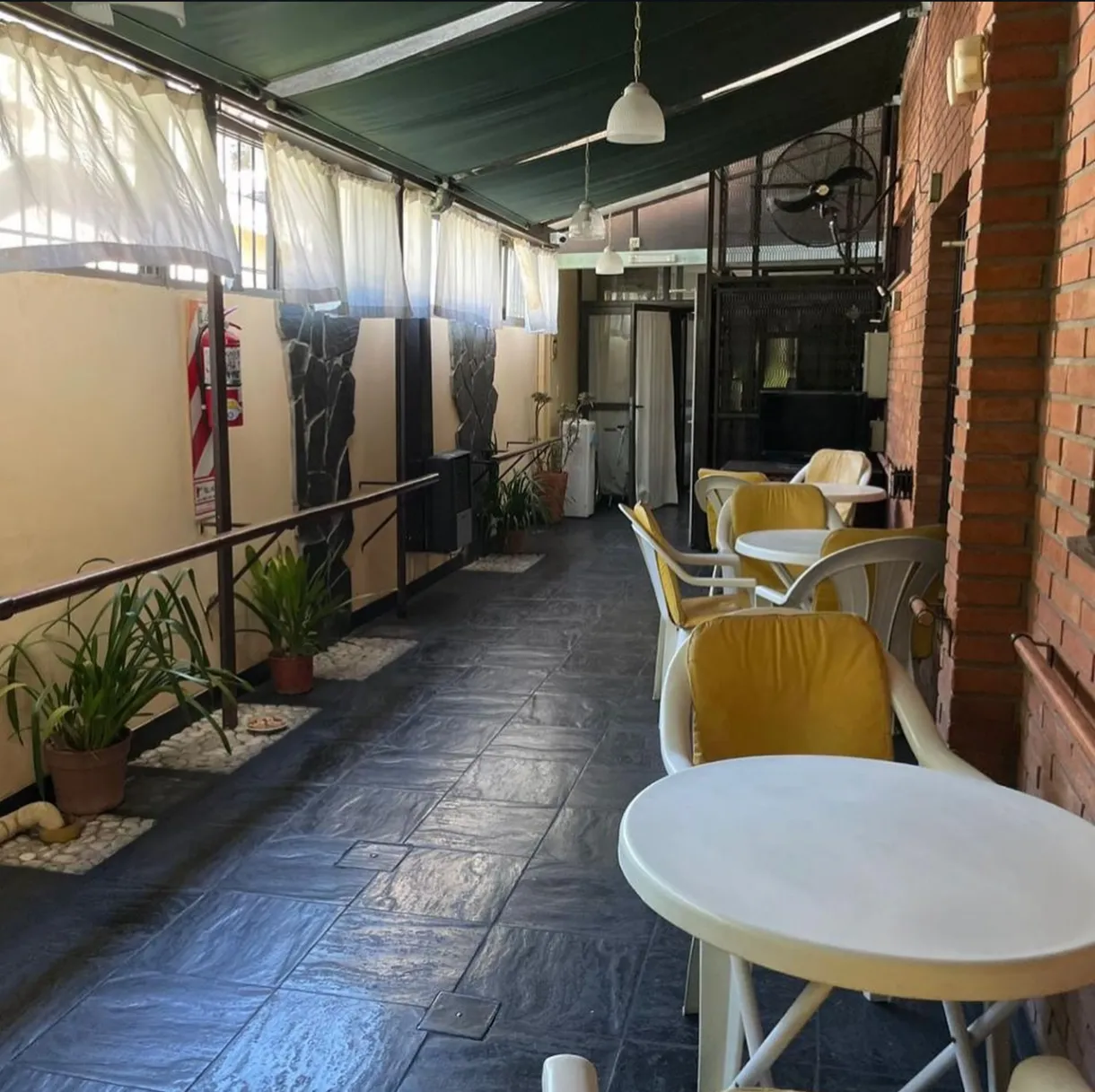 Galería cubierta con mesas, sillas y plantas