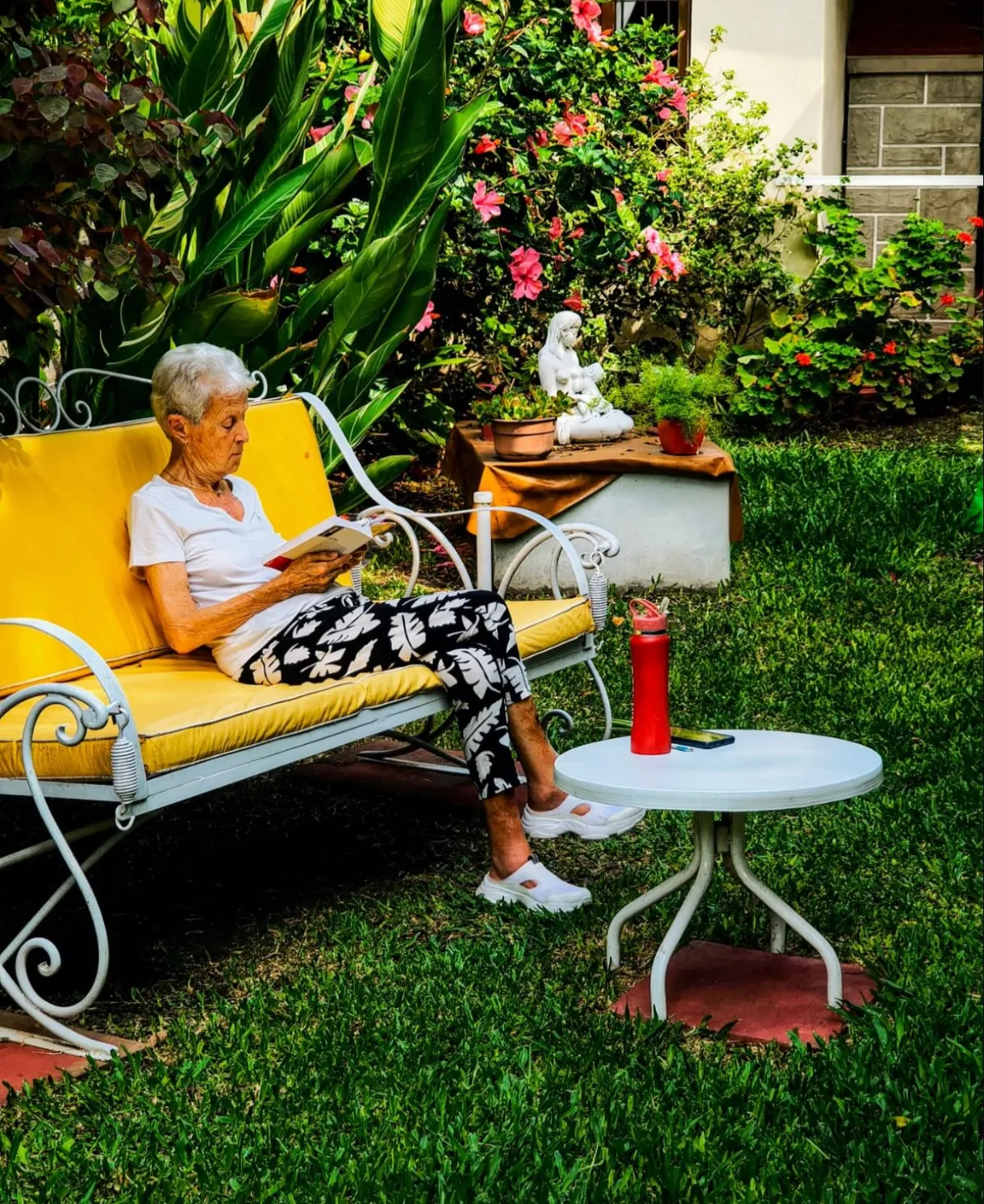 Persona mayor leyendo en un banco del jardín de Casa San Juan